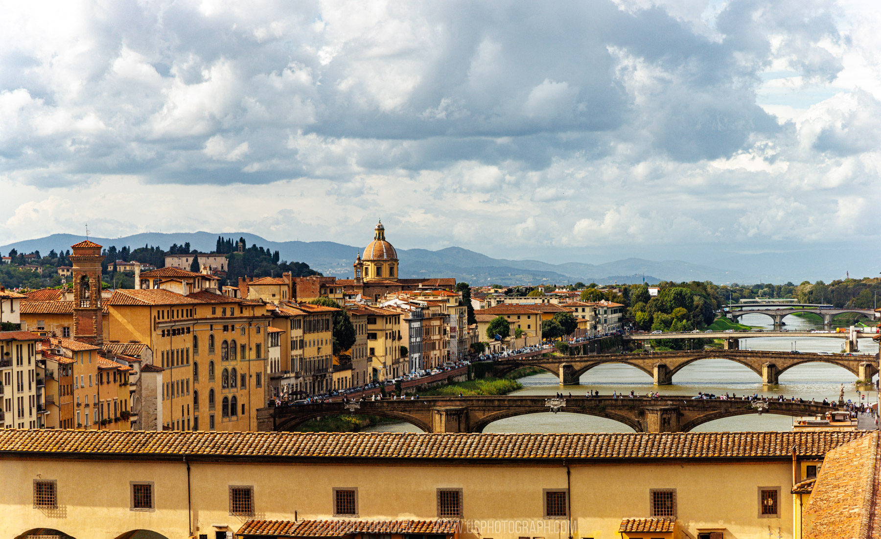 Arno River bridges and terracotta rooftops under dramatic clouds in Florence, Italy, color travel photography