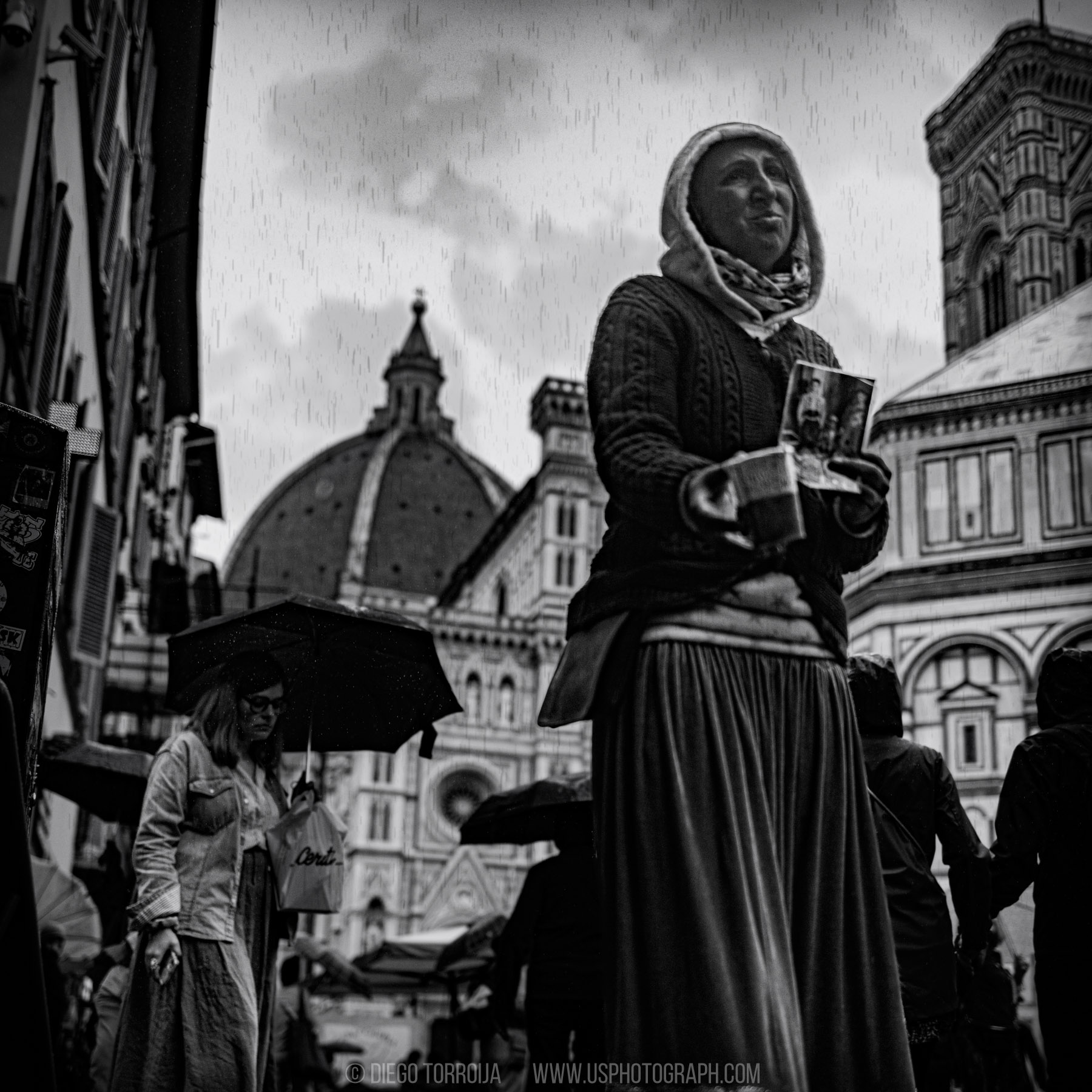 Woman in a headscarf in the rain with the Florence Duomo dome behind her, black and white street photography