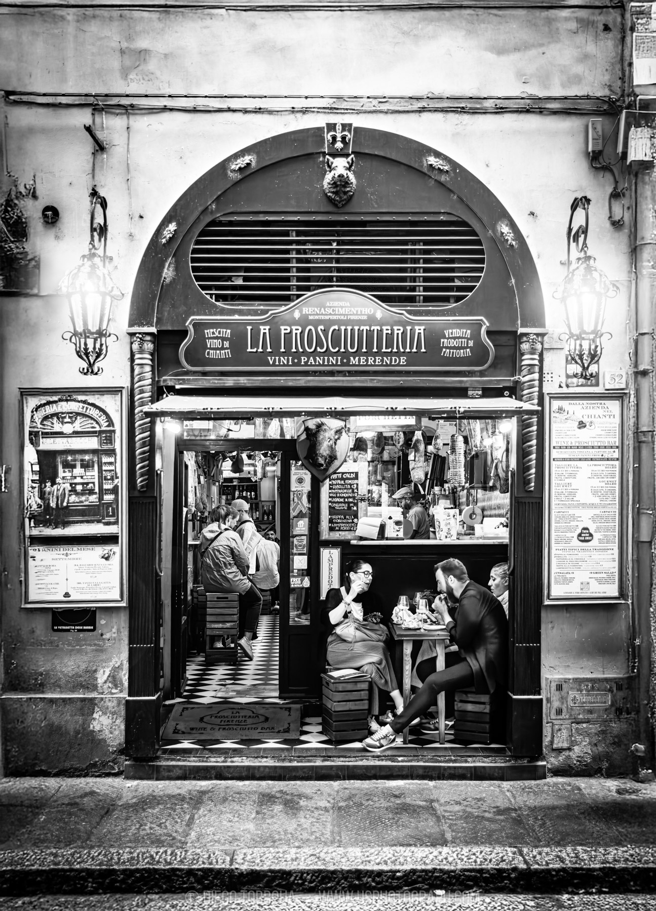 Diners inside a classic prosciutto and wine bar storefront in Florence, black and white street photography