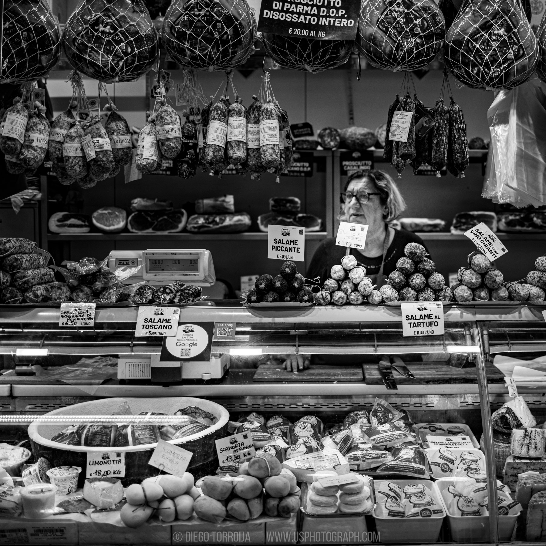 Italian salumeria counter with hanging prosciutto and salami in Florence, black and white street photography